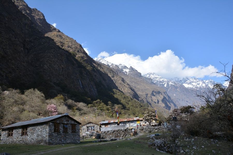 Stone teahouses with snow-capped Himalayan peaks rising dramatically in the background
